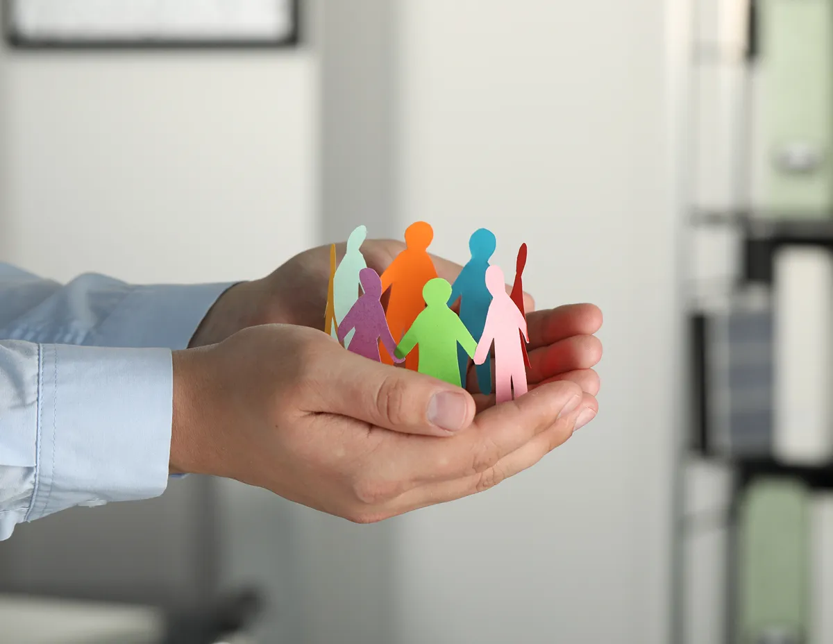 Muž drží papírové postavy jako symbol spolupráce